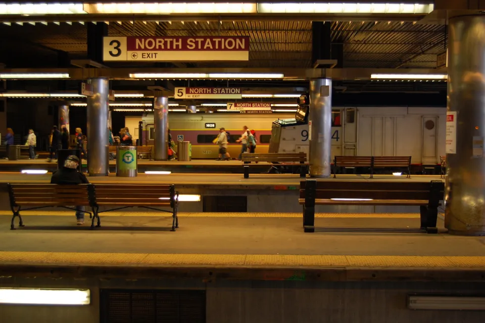 Few passengers waiting in subway station with multiple platforms and "North Station" signs in Boston, Massachusetts